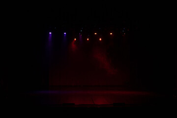 An empty stage of the theater, lit by spotlights and smoke before the performance