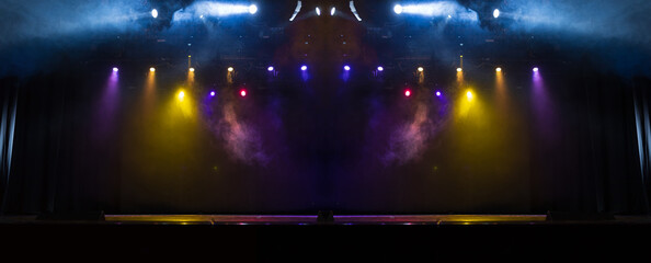 An empty stage of the theater, lit by spotlights and smoke before the performance