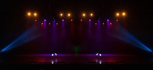An empty stage of the theater, lit by spotlights and smoke before the performance