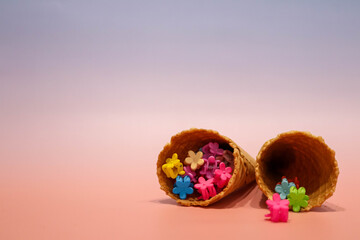 Colorful flower hair clips spilling from waffle cones on pastel background