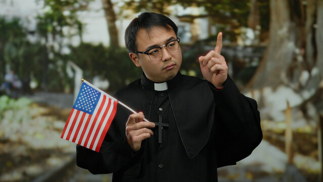 Young man dressed as priest holding american flag in a park setting, blending religious symbolism with national identity in an outdoor environment.
