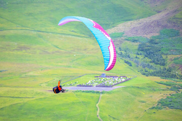 Colorful paraglider soaring above green hills in Iceland's stunning landscape