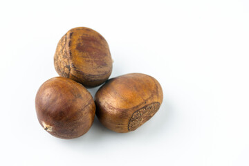 Close-up of fresh brown chestnuts isolated on white background, showing natural texture and detail....