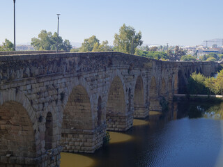 Naklejka premium Longest ancient Roman bridge still in use. Historical stone arches crossing the river in Merida, Spain, a UNESCO World Heritage site under a clear blue sky.