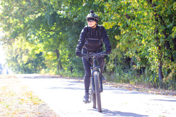 Cyclist enjoying a sunny day on a tree-lined path during autumn in the countryside