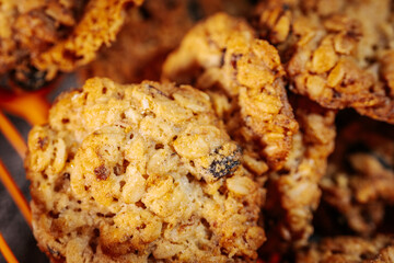 Detailed view of golden-brown oatmeal raisin cookies with visible oats and dark raisins on a white background. Crisp edges and chewy center. 