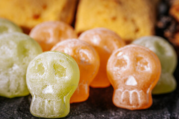 A close-up of green and orange skull-shaped candies covered in powdered sugar, perfect for Halloween-themed snacks.