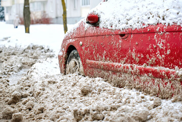 Car trapped under dirty snow piles. Automobile car tire buried under thick frozen slush after blizzard. Winter roadside with vehicle blockage after snowplow cleanup operation in cold weather season.