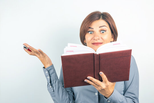 Woman expressing surprise while reading a notebook in a bright setting indoors