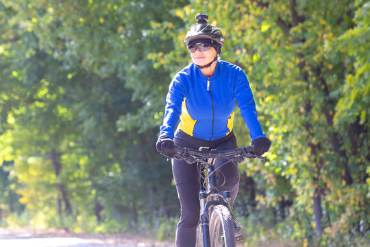 Woman enjoys a sunny bike ride on a forest path in autumn