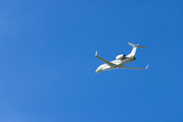 Private jet flying high in clear blue sky