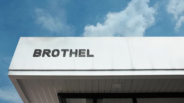 Brothel word sign displayed on the exterior of a building under a clear blue sky, symbolizing adult entertainment, commercial establishment, nightlife, and related services