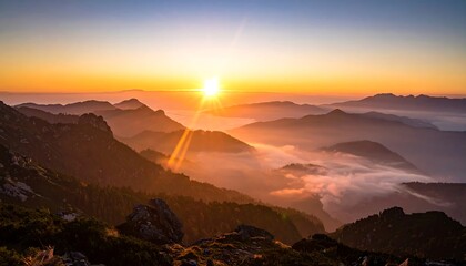 Mountainous landscape with a sunburst rising over misty peaks, illuminating the scene with an orange glow
