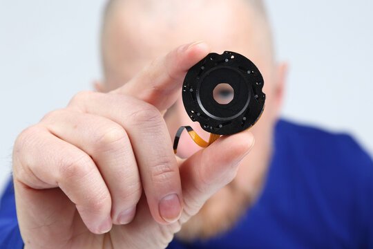Expert technician demonstrates camera lens component repair in a workshop setting