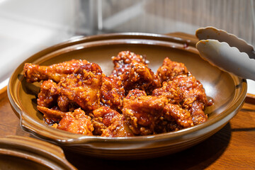 Korean fried chicken perfectly fried to a golden crisp and coated with sauces on ceramic bowl
