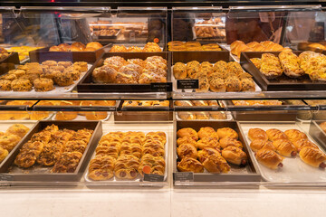 Assorted pastry and bread arranged on tray selling at bakery shop.