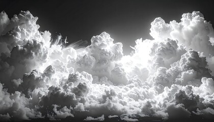 Monochrome photograph of a vast, towering cloudscape illuminated by sunlight. Dark sky contrast with brilliant fluffy formations