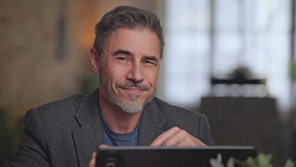 Portrait of happy confident mid adult businessman looking at camera, smiling. Middle aged male entrepreneur working with laptop at home or office. Trust, success, reliability in business.