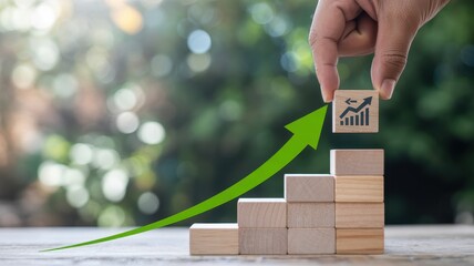 Hand placing wooden block with growth chart on stacked blocks symbolizing financial progress