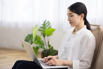 Woman Sitting on Sofa Using Laptop in Bright Living Room