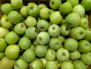 Pile of fresh, ripe green apples displayed in a wooden crate, showcasing nature's bounty and healthy eating
