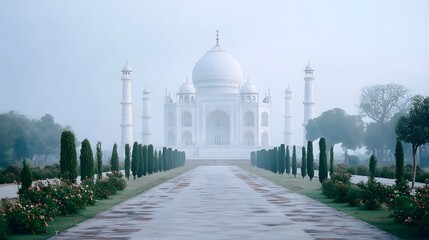 Ethereal morning mist gently shrouds the majestic Taj Mahal a world renowned white marble mausoleum approached by a symmetrical garden pathway lined with trees and flowers