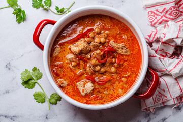 Tikka masala with chicken and chickpeas in red pot.