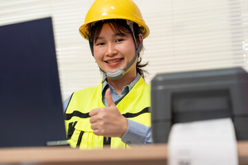 Asian female engineer uses a laptop or notebook to print barcode stickers on a barcode printer and thumps up.