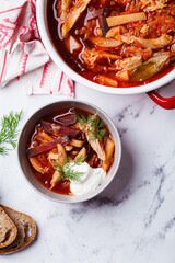 Classic homemade borscht with chicken in a grey bowl.