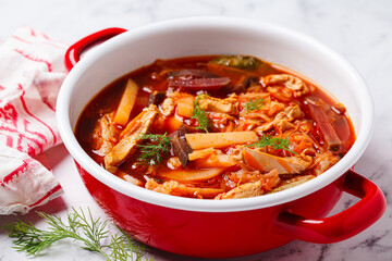 Classic borscht with chicken in a red pot.