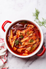 Classic borscht with chicken in a red pot.