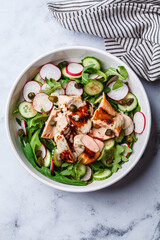 Salad with grilled salmon, cucumber, radish, capers and tahini dressing.