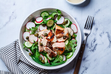 Salad with grilled salmon, cucumber, radish, capers and tahini dressing.
