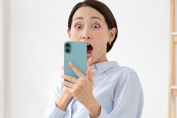 スマホを持って驚く女性