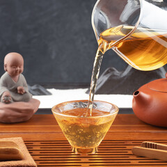 Pouring tea from teapot into cup on tea mat