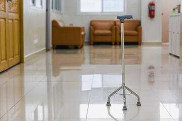 Four-legged walking cane with a blue handle against a white wall.
