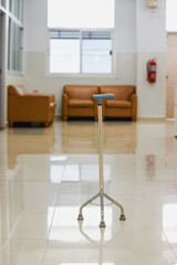 Four-legged walking cane with a blue handle against a white wall.