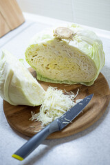 Close-up of white cabbage on a wooden board with a knife, shredder for sourdough.