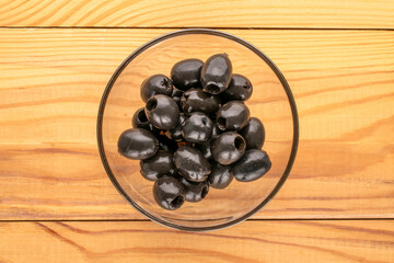 Canned black pitted olives on a wooden table, top view.
