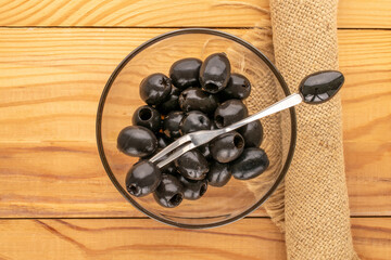 Canned black pitted olives on a wooden table, top view.