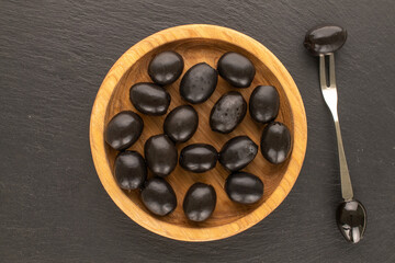 Canned pitted black olives on slate stone, top view.
