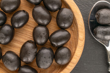 Canned pitted black olives on slate stone, top view.