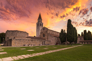 Basilica of Aquileia surrounded by cypress trees during the golden hour. The upcoming sun...