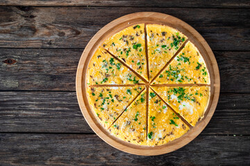 Frittata - scrambled eggs with feta cheese and parsley on wooden table. Top view	