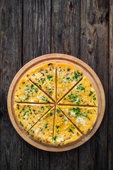 Frittata - scrambled eggs with feta cheese and parsley on wooden table. Top view	