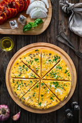 Frittata - scrambled eggs with feta cheese and parsley on wooden table. Top view	