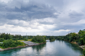 View from a river dam with an artificial fish ladder and forest in the background under dramatic...