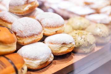 Delicious sweet Polish pastries, donuts with powdered sugar and pistachio cream, on display in a cafe