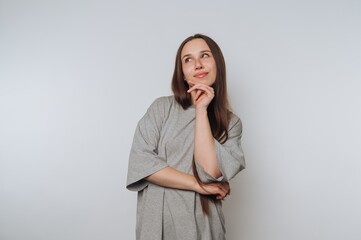 Young woman in gray shirt pondering against white background