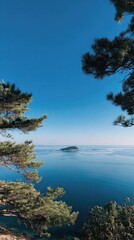 Fototapeta premium Serene ocean view, small island framed by trees under a clear blue sky